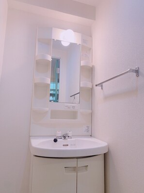 Un bagno con un lavandino bianco, uno specchio e un portasciugamani.
