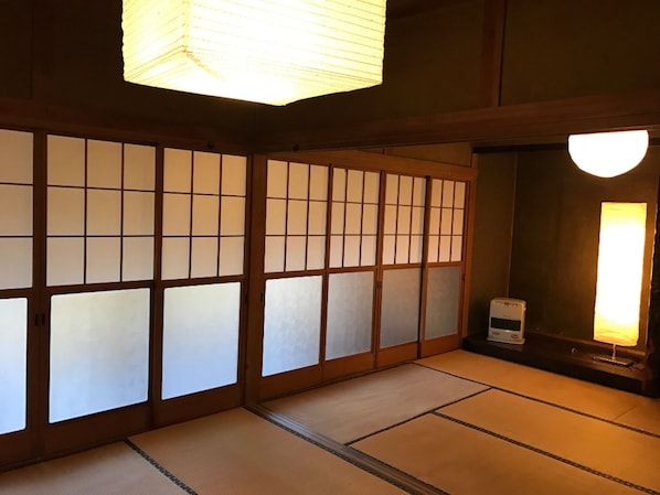 A traditional Japanese room with tatami flooring, sliding shoji doors, and a ceiling light fixture.