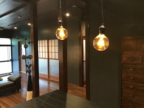 A modern interior with wooden floors, a dark green wall, and a traditional Japanese sliding door in the background.