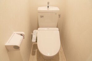 Sanita com painel de controlo e suporte para papel higiénico.