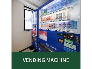 Ein Getränkeautomat mit verschiedenen Getränken und Snacks, ein Honda-Schild und LED-Beleuchtung.