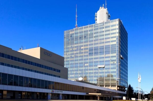 A modern building with a glass facade and a smaller adjacent structure with a flat roof.
