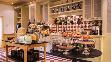 Una mesa de buffet con diversas opciones de panadería y pastelería a la vista.