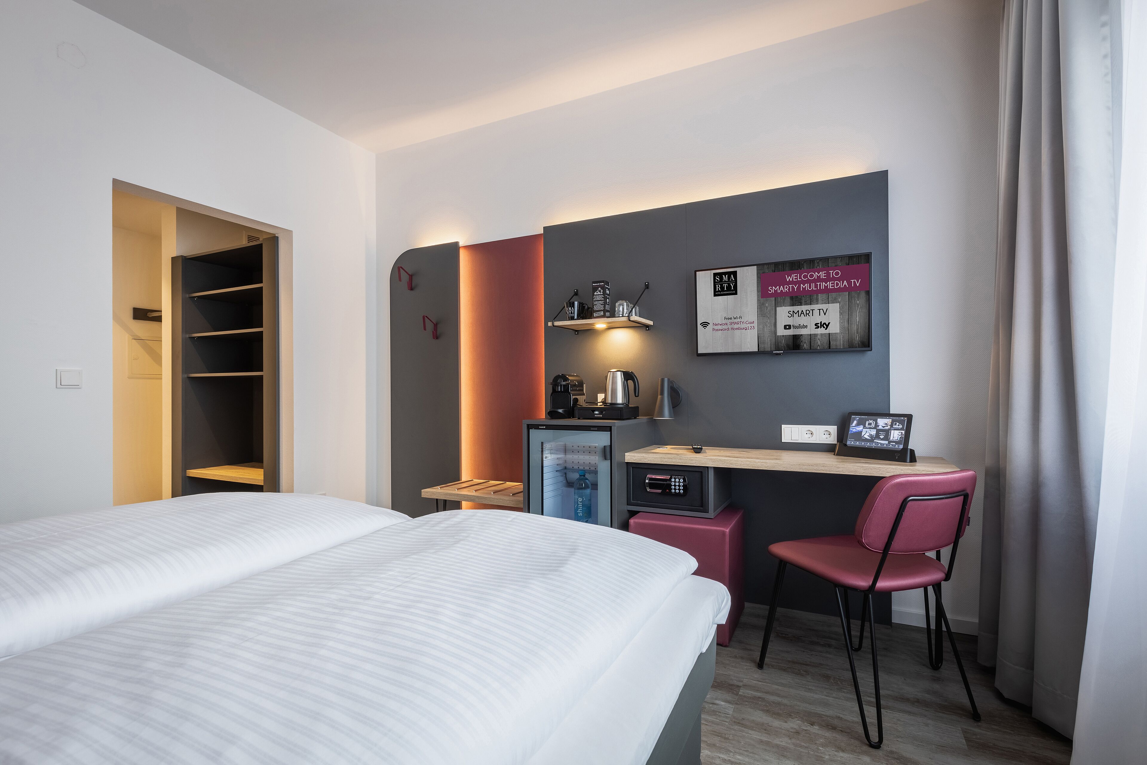 Une chambre d’hôtel comprenant un lit, un bureau avec une chaise, un mini-réfrigérateur, une machine à café et un téléviseur.