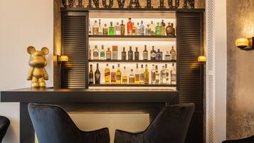 A bar area with shelves of liquor bottles, a bear figurine, and two black chairs.