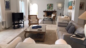 A spacious living room with a fireplace, comfortable seating, and a television. - Villa Amfitriti - Mykonos Guests 6 (Mykonos)