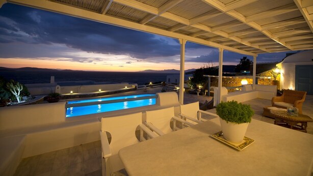 A modern outdoor patio with a pool, seating, and a view of the sea at dusk. - Villa Amfitriti - Mykonos Guests 6 (Mykonos)