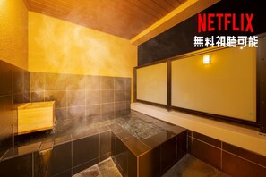 A modern bathroom with a wooden bench, a shower area, and a large mirror.