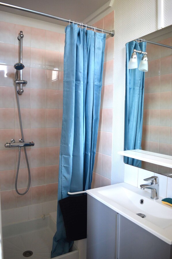 Un baño con ducha, lavamanos y espejo.