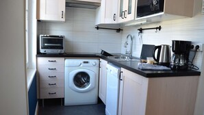 A compact kitchen with a washing machine, dishwasher, microwave, and coffee maker. - 2 steps from the beach - Centre d'Asnelles (Asnelles)