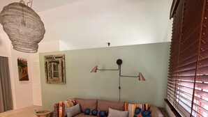 Een gezellige woonkamer met een hoekbank, een glazen salontafel en een hanglamp.