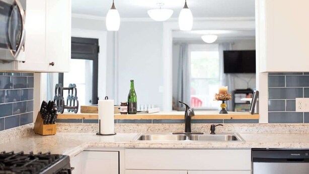 A modern kitchen with a stainless steel sink, a built-in stove, and pendant lighting. - Spacious Cityside House w/ Game Room & Fire Pit (Geneva)