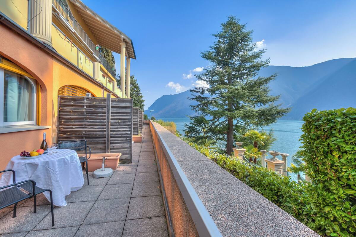 A terrace with a table set for dining, a view of the lake, and a mountain in the background.