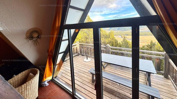 A room with a large triangular window offering a view of a wooden deck and outdoor furniture. - Chalet for 6 with balcony and parking in Les Angles (Les Angles)