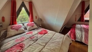 A bedroom with a sloped ceiling, a bed with a patterned bedspread, and red curtains. - Chalet for 6 with balcony and parking in Les Angles (Les Angles)