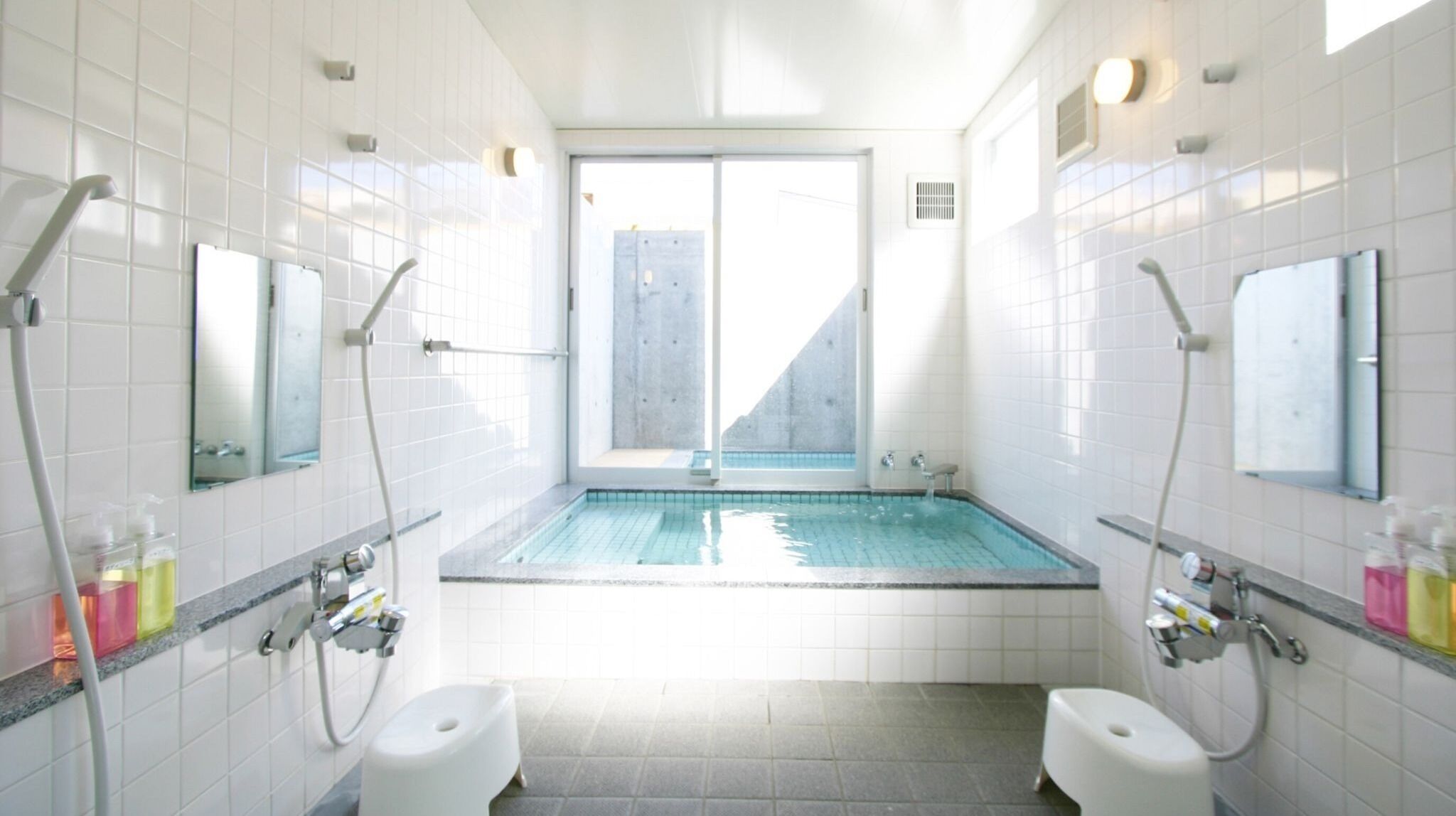 Ein modernes Badezimmer mit einem zentralen Pool, zwei Toiletten und einem großen Fenster.