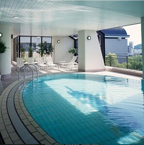 Relax by the pool surrounded by a spacious deck with lounge chairs and a table.