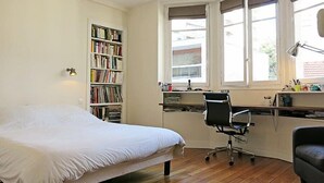 A bedroom with a bed, a desk, a chair, a bookshelf, and a window with curtains. - Charme Vaugirard Procession CityCosy (Paris)