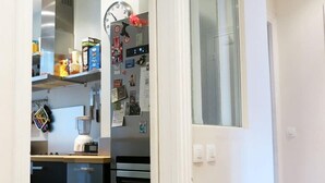 A compact kitchen with a refrigerator, a clock, and various kitchen items on the wall. - Charme Vaugirard Procession CityCosy (Paris)