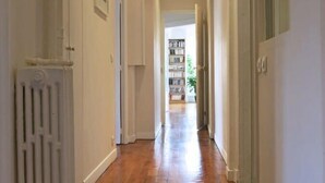 A hallway with wooden flooring, white walls, and a radiator on the left. - Charme Vaugirard Procession CityCosy (Paris)