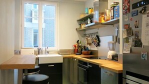 A compact kitchen with a window, a sink, a stove, and a refrigerator. - Charme Vaugirard Procession CityCosy (Paris)