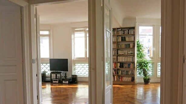 A spacious living area with wooden flooring, a television, a bookshelf, and a potted plant. - Charme Vaugirard Procession CityCosy (Paris)
