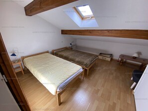 A small, single-room apartment with a sloped ceiling, a skylight, a bed, a desk, and a small table. - Fully equipped T4 apartment - Sleeps 6 - Les Angles (Les Angles)