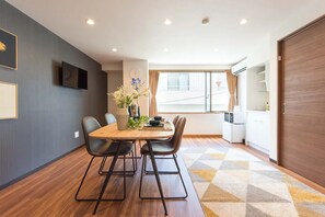 A dining area with a wooden table, black chairs, a vase with flowers, and a television on the wall.