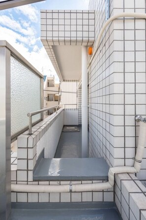 Un couloir intérieur étroit, aux murs recouverts de carreaux et doté d’une rambarde en métal.