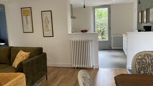 Un salon moderne avec un canapé vert, une table à manger et un coin cuisine avec une fenêtre.