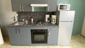A compact kitchen with grey cabinets, a built-in oven, a microwave, and a coffee maker.