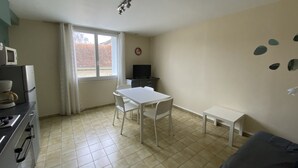 A compact kitchen with a dining area, a TV, and a window with curtains.