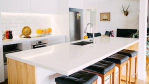 Et moderne køkken med en stor ø, rustfrie hvidevarer og et minimalistisk design.