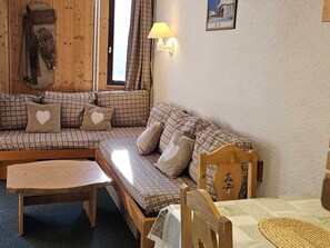 Une pièce chaleureuse avec un canapé à carreaux, une table en bois et une chaise.