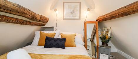 A bedroom with a bed, a nightstand, a mirror, and a wall-mounted shelf.