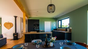 A modern kitchen with a central island, a dining area with a round table set for four, and a cozy seating area with a sofa.