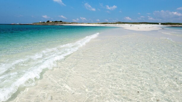 A beach with clear turquoise water and white sand.