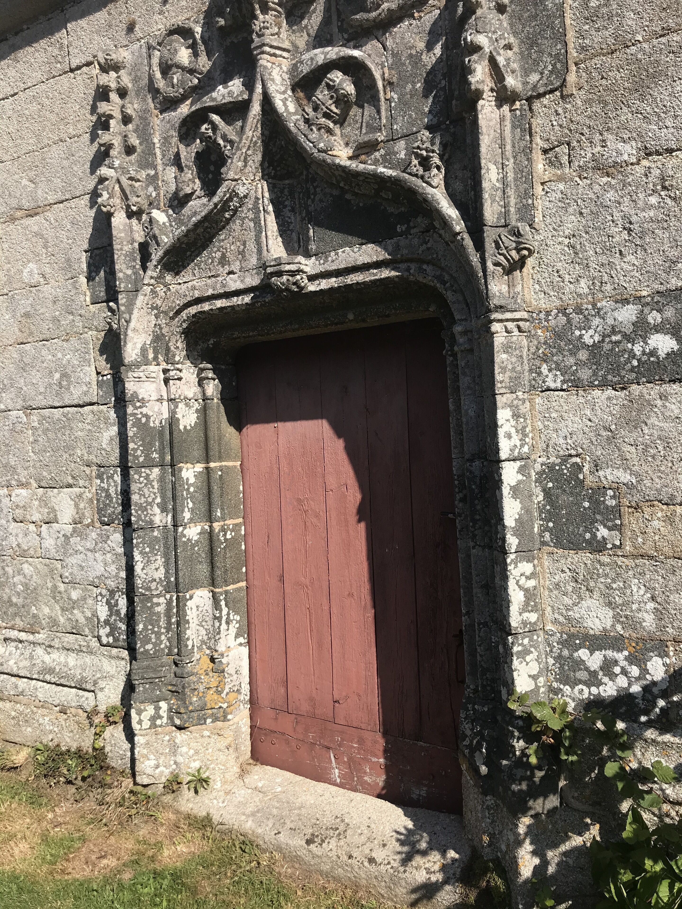 A stone building with a red door and intricate carvings.