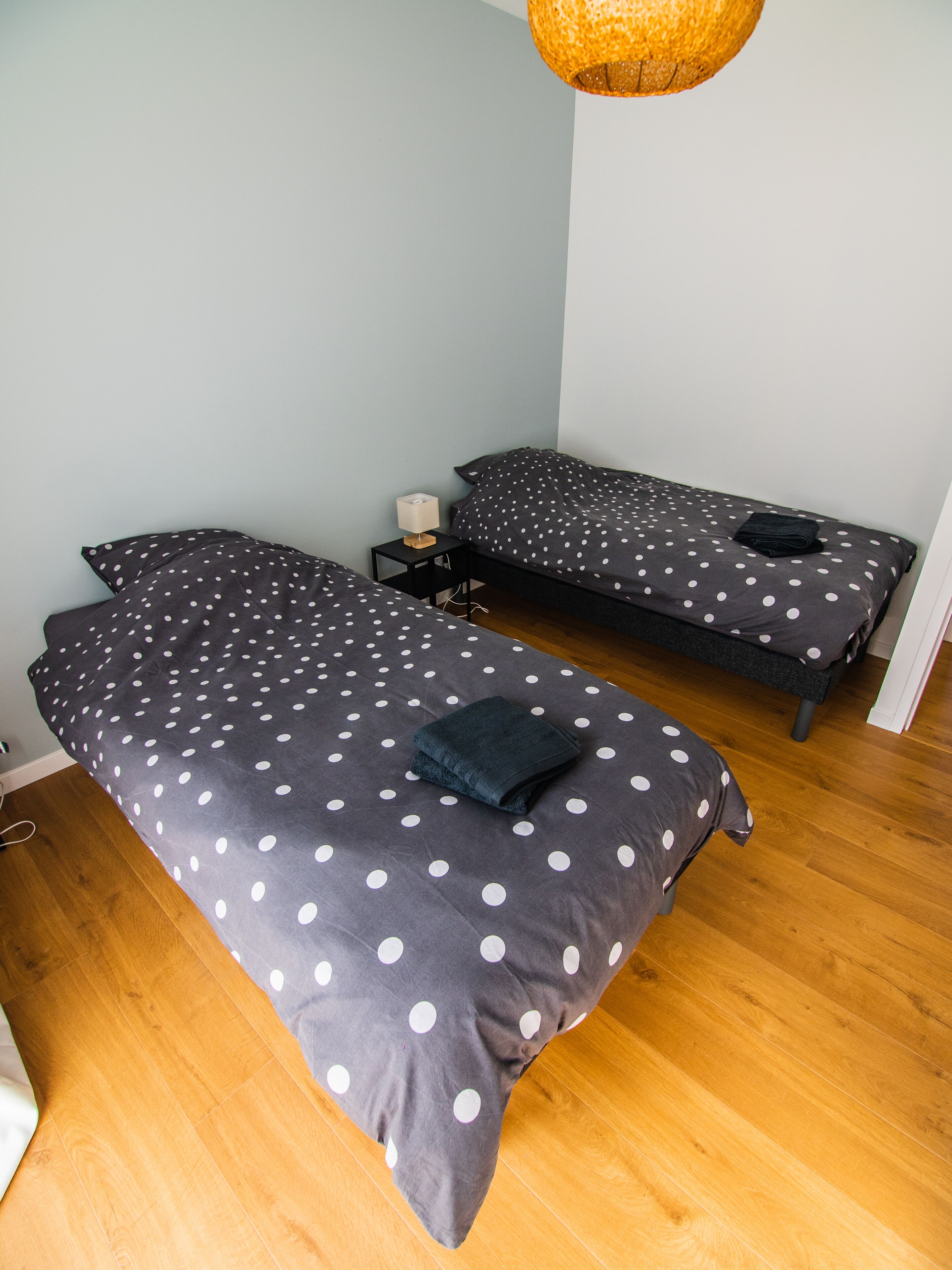 A room with two single beds, each with a polka dot duvet and a small bedside table with a lamp.