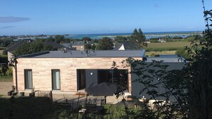 A modern house with a flat roof, large windows, and a view of the sea.