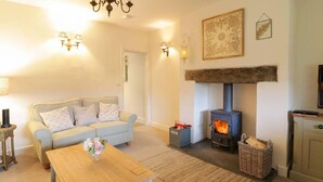 A cozy living room with a sofa, a wooden coffee table, a fireplace, and a television. - Lovely 2-bed Cottage in Blaenau Ffestiniog (Blaenau Ffestiniog)