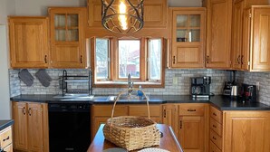 Una cocina con armarios de madera, una isla central con una cesta y una lámpara colgante.