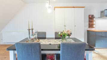 A dining area with a table set for four, a chandelier, and a cabinet with a shelf.