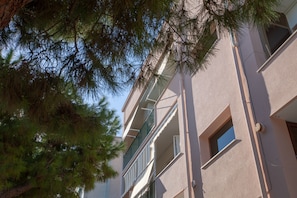 Residents enjoy balconies with green railings and natural light from windows on each floor.