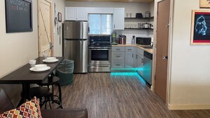 Een moderne keuken met roestvrijstalen apparatuur, een eethoek met tafel en stoelen, en een houten plafond.