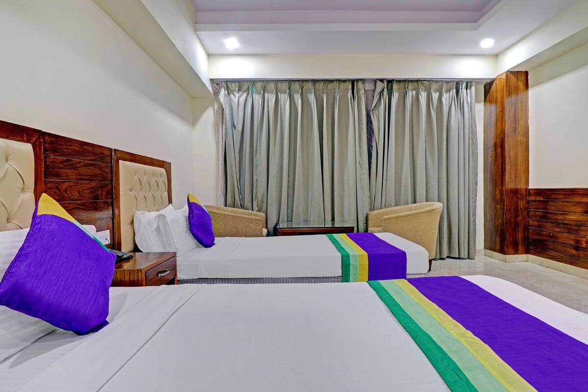 Ein Hotelzimmer mit zwei Betten, einem Holzkopfteil, einem kleinen Tisch und einem Stuhl.
