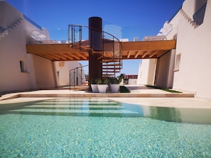 A pool area with clear water, a wooden staircase, and potted plants. - La Corte Residence (Salve)