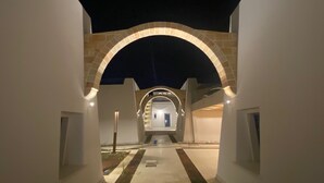A covered walkway leading to a building entrance with a stone archway and a door. - La Corte Residence (Salve)