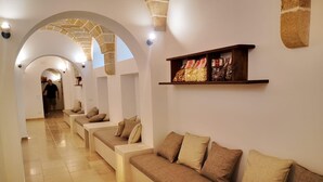 A hallway with a series of sofas and a shelf with snacks. - La Corte Residence (Salve)