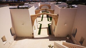 A rooftop terrace with a geometric pathway leading to a central archway, surrounded by white walls and potted plants. - La Corte Residence (Salve)